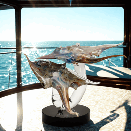 Scultura manta doppia in vetro calcedonio di Murano su base nera , fotografata con vista mare - elegante opera artigianale italiana